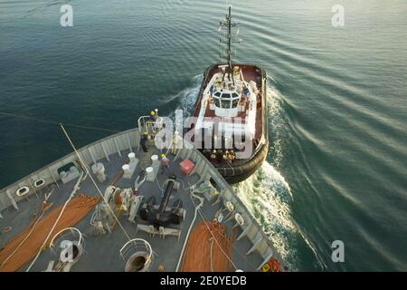 Line handlers aboard the roll-on-roll-off and container ship MV Cape Ray (T-AKR 9679) work with an Italian tugboat to moor the ship upon arriving at the Medcenter Container Terminal in Gioia Tauro, Italy 140701 Stock Photo