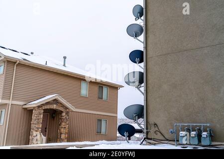 Parabolic satellite dishes and electricity meters on exterior wall of building Stock Photo