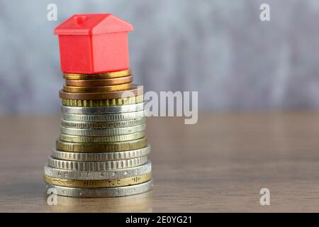 House is sitting on top of a coin stack, Real Estate and Savings Concept Stock Photo