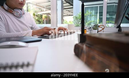 Graphic designer with headphone typing on keyboard at his creative workspace. Stock Photo