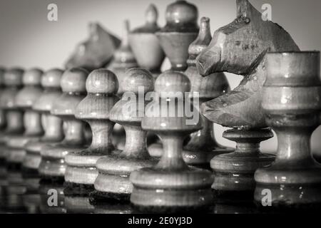 Wooden chess pieces stand on the board in the starting position before the battle. Stock Photo