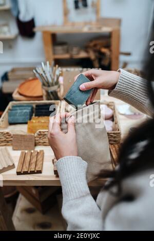 Woman hands putting eco soap in a fabric bag. View from behind shoulder. Stock Photo