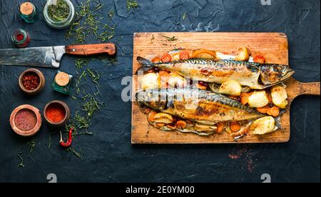 Delicious mackerel fish roasted with apples,served on kitchen board. Stock Photo