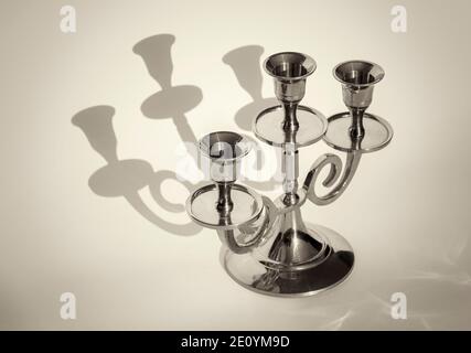 Golden candlestick on a white background with shadows close-up. Stock Photo
