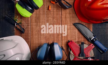 Construction site safety. Protective hard hat, headphones, gloves, glasses and masks on wooden background, copy space, top view Stock Photo