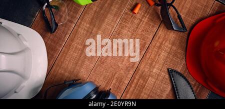 Construction site safety. Protective hard hat, headphones, gloves, glasses and masks on wooden background, copy space, top view Stock Photo