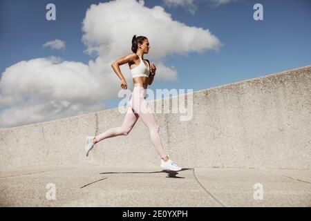 Woman in sportswear running. Woman runner in jogging outfit running outdoors. Stock Photo