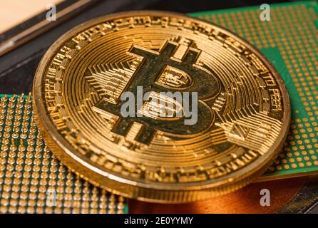 Golden coin with bitcoin symbol on a mainboard Stock Photo