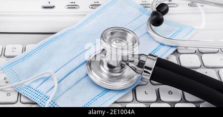 Face mask and stethoscope with PC keyboard Stock Photo