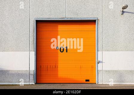 concrete wall with an orange gate with roller shutters, January 2, 2021, Frederikssund, Denmark Stock Photo