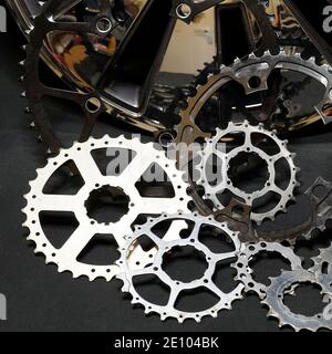 Cog wheels of bicycles and  part of a wheel cover on a black background. Steampunk. Bicycle. Technical. Mechanical parts. Gears. Cogwheels Stock Photo