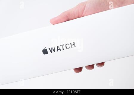 Apple watch box in woman hand on the grey background with copy space, December 2020, San Francisco, USA Stock Photo