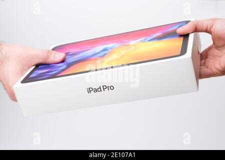 Man and woman hand holding a box with IPad Pro on the grey background, December 2020, San Francisco, USA Stock Photo