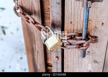Combination padlock and rusty iron chain securing the door of outdoor bathroom Stock Photo