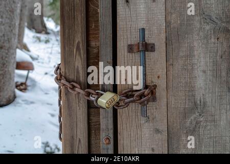 Close up of combination padlock and rusty chain on old wooden bathroom door Stock Photo