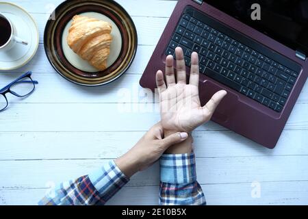 man suffering pain in hand while working on laptop  Stock Photo