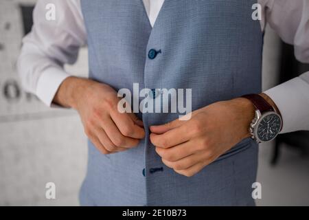 man buttons up the buttons of a blue suit jacket Stock Photo