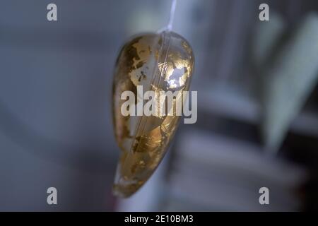 Old treasured Christmas heart ornament viewed side on with worn textured gold outer and lateral copyspace Stock Photo