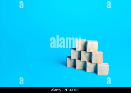 Wooden blocks pyramid on a blue background. Slide for presentation. Copy space, place for text. Steps. Minimalism. Simple shapes geometry. Stock Photo
