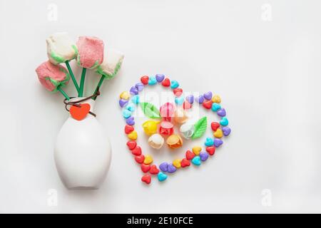 Creative composition of colorful candies and marshmallows on a stick in the shape of a rose on a light background. copy space. Stock Photo