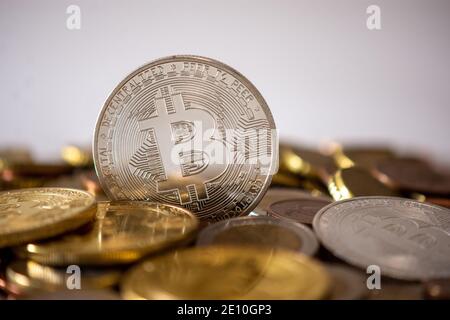 A silver bitcoin standing among many blurred coins. Bitcoin is a cryptocurrency, a decentralized digital currency without a central bank Stock Photo