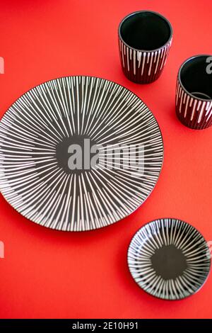 a grey ceramic plate set on a red background portrait Stock Photo
