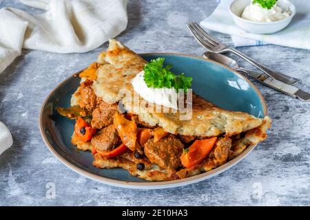 Traditional Hungarian goulash with potato pancake and cream Stock Photo