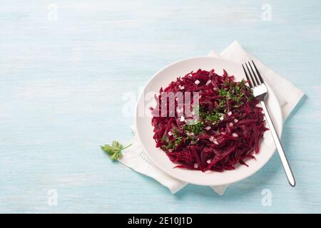 Healthy detox raw beetroot salad with red onion, garlic, herbs and spices on a blue background. diet food. top view, free space Stock Photo