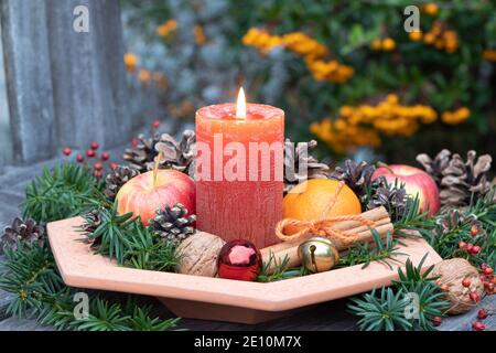christmas decoration with candle, pine cones, apple and mandarin in the plate Stock Photo