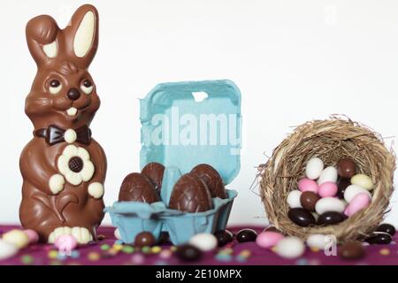 Chocolate bunny, egg carton with chocolate eggs and bird nest with sweet almonds Stock Photo
