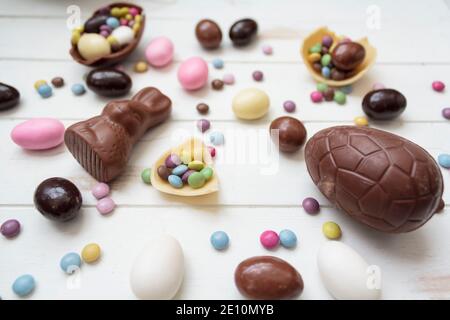 Easter candies on white wooden table. Chocolate eggs, chocolate bunny and other easter sweets Stock Photo