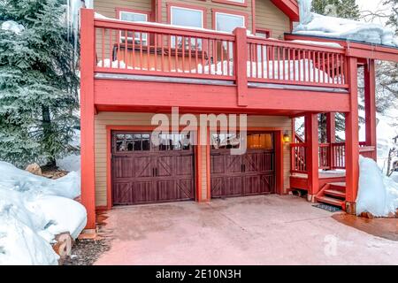 House with snowy roof and balcony in winter above attached two car garage Stock Photo