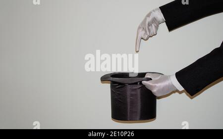 Portrait of young black Illusionist magician doing magic with a top hat and a magic wand isolated on a white background Stock Photo