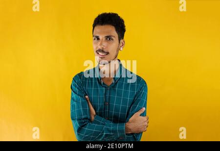 Black young man in a green social shirt, isolated on yellow background Stock Photo