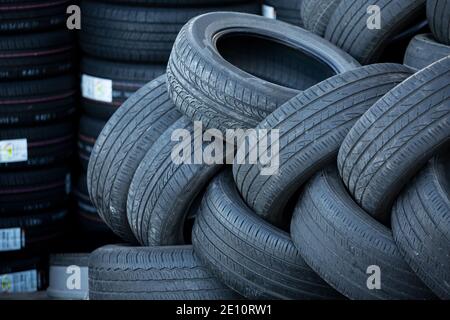 Pile of used tires on a background of new tires Stock Photo