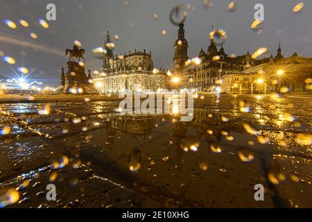 Dresden, Germany. 03rd Jan, 2021. The equestrian statue of King Johann (l-r), the Hofkirche, the Hausmannsturm, the Residenzschloss and the Schinkelwache are reflected in a puddle on Theaterplatz in the evening. Credit: Robert Michael/dpa-Zentralbild/dpa/Alamy Live News Stock Photo