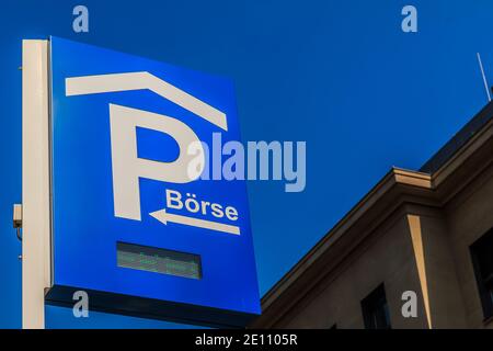 Traffic sign parking lot with LED writing. Blue parking sign of the Frankfurt Stock Exchange on a pole. Blue sky with house facade in the background Stock Photo
