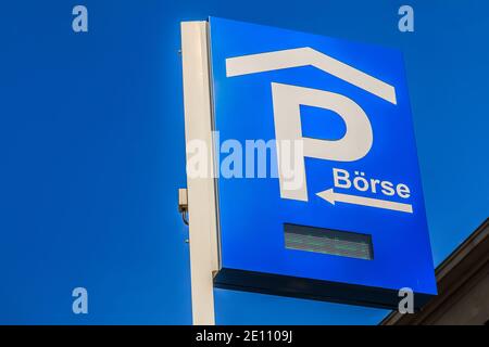 Sign parking lot with LED writing. Blue parking sign of the Frankfurt Stock Exchange on a pole. Road sign under blue sky with house facade in the back Stock Photo