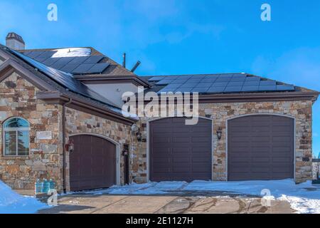 Home exterior with three garage doors and solar panels mounted on the roof Stock Photo