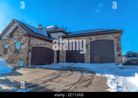 Home with three car garage solar panels mounted on roof and stone brick wall Stock Photo