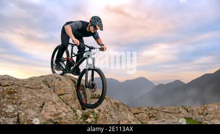 Professional Cyclist Riding Bike on the Autumn Rocky Trail at Sunset. Extreme Sport and Enduro Biking Concept. Stock Photo