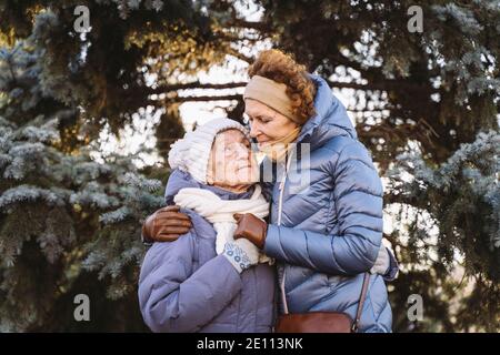 Motherhood. Theme importance visiting and spending time with old single parents during holidays. Senior mom and mature daughter happy family hug and l Stock Photo