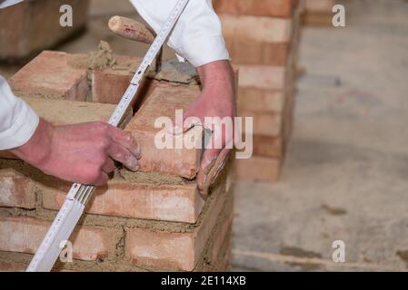 Mason Walls Brick Wall With The Help Of A Trowel And Folding Rule - Close-up Stock Photo