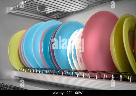 Clean dishes drying on metal racks for dishes on the shelves. Storing clean kitchen utensils and drying them. Stock Photo