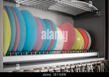 Clean dishes drying on metal racks for dishes on the shelves. Storing clean kitchen utensils and drying them. Stock Photo