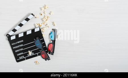 Cinema clapperboard, colourful 3d glasses and popcorn on white wooden background top view. Cinema background. Stock Photo