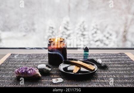 Palo Santo wood known as oily aromatic holy wood sticks smouldering on plate on home window sill cleaning negative energy concept. Beautiful winter. Stock Photo