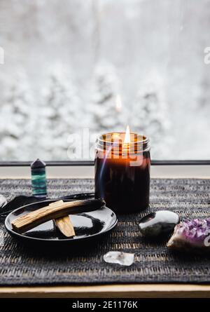 Palo Santo wood known as oily aromatic holy wood sticks smouldering on plate on home window sill cleaning negative energy concept. Beautiful winter. Stock Photo