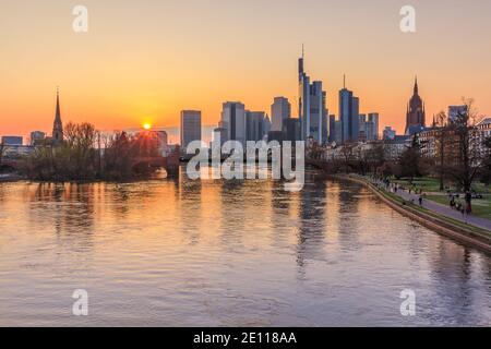 Sunset over the Frankfurt skyline. Skyscrapers, commercial buildings on the horizon. River Main with bridge and park on the bank. Reflections of the s Stock Photo