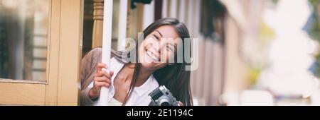 Smiling Asian woman taking pictures on Trolley street car ride with vintage camera panoramic banner. Tourist riding public transit tramway system in Stock Photo